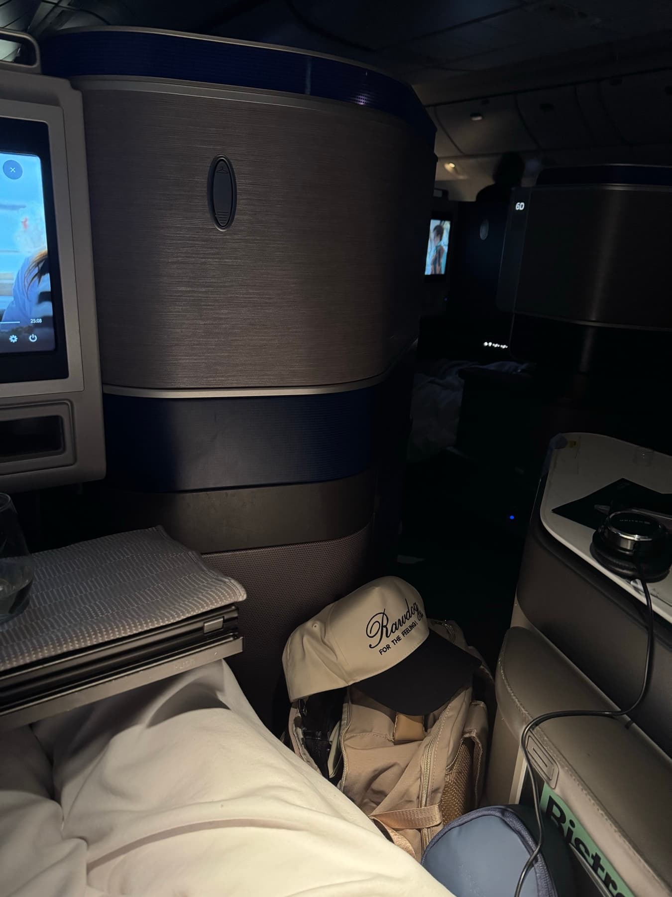 RAWDOG Trucker Hat packed beside an airplane seat